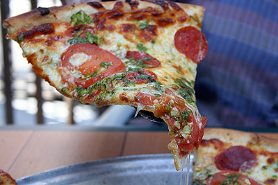 Pepperoni, pesto, broccoli, garlic, and tomato pizza