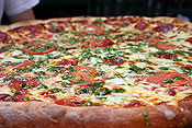 Pepperoni, pesto, broccoli, garlic, and tomato pizza